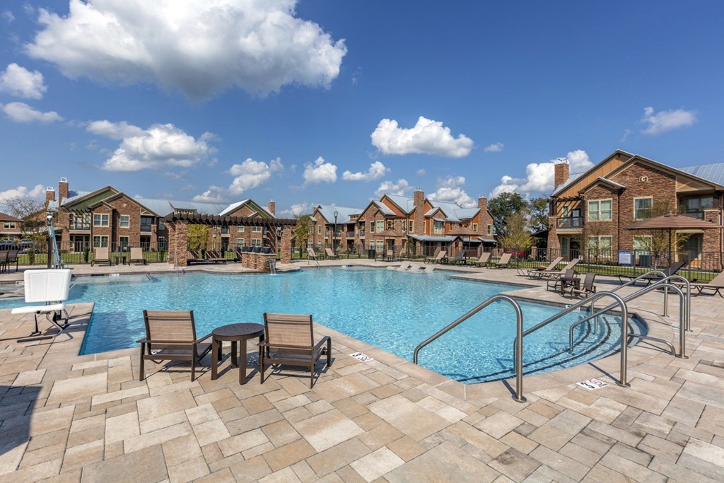 A swimming pool surrounded by chairs and a building in the background.