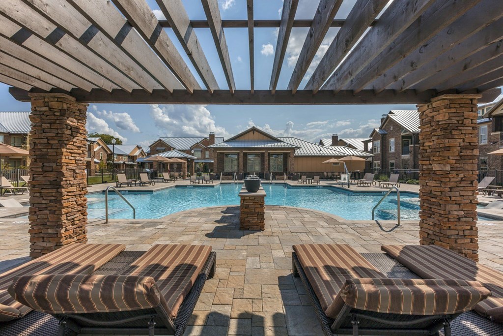 A pool surrounded by wooden benches and a wooden pergola.