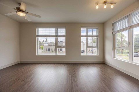 A room with a ceiling fan and two windows.