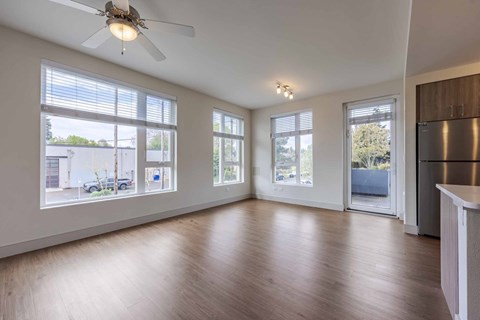 A spacious room with a ceiling fan and large windows.