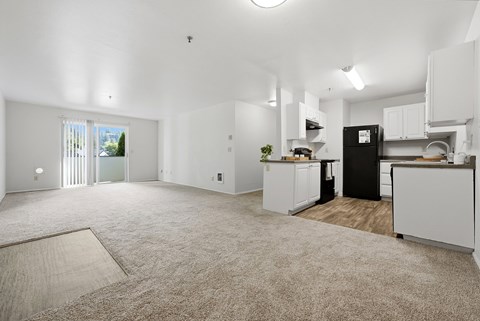 A spacious kitchen with white cabinets and a black refrigerator.