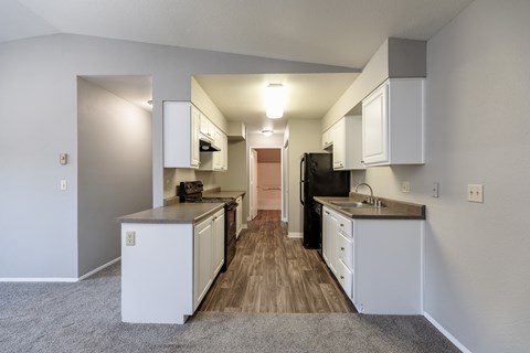 A kitchen with white cabinets and a black refrigerator.