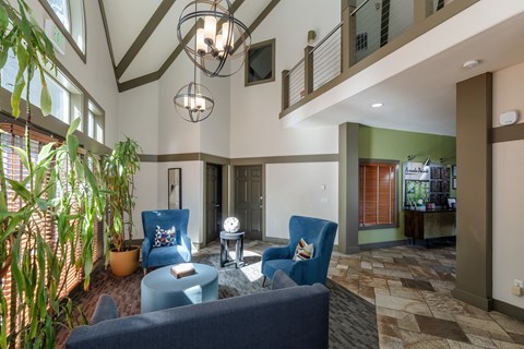 A living room with a blue couch and a hanging light fixture.