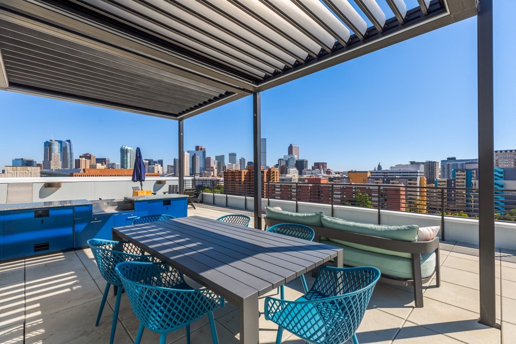 a rooftop patio with a table and chairs and a view of the city