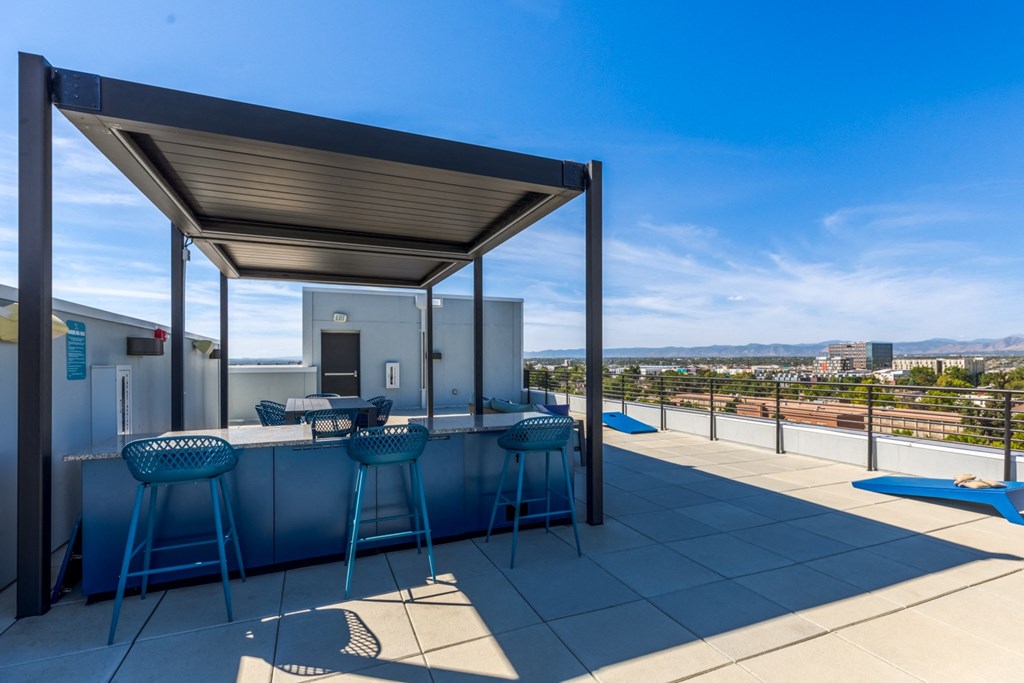 a rooftop bar with bar stools and a view of the city