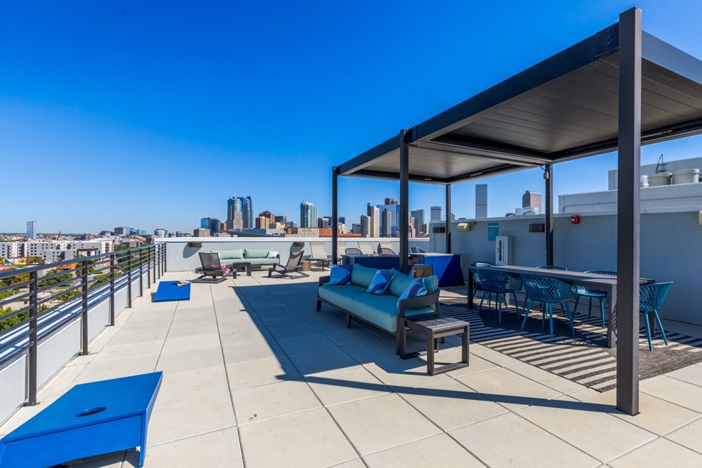 a rooftop patio with blue furniture and a city in the background