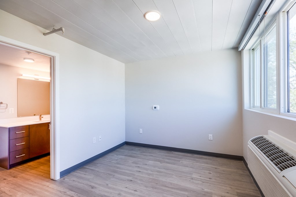 an empty bedroom with wood flooring and a large window