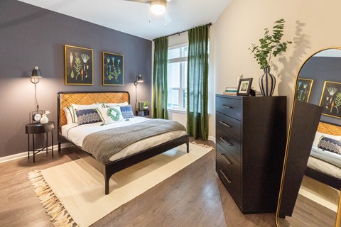 A bedroom with a bed, nightstand, and a dresser with a mirror.