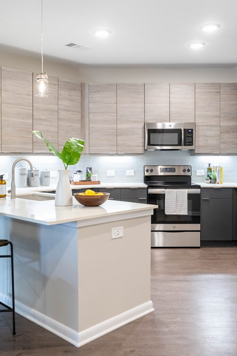 A kitchen with a white counter and a bowl of fruit on it.