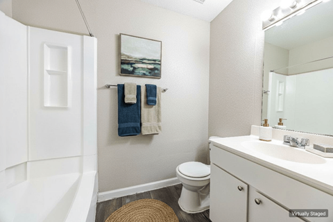 A bathroom with a toilet, sink, and a painting on the wall.