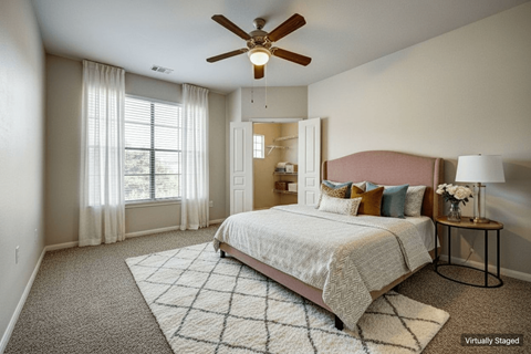A bedroom with a large bed and a ceiling fan.