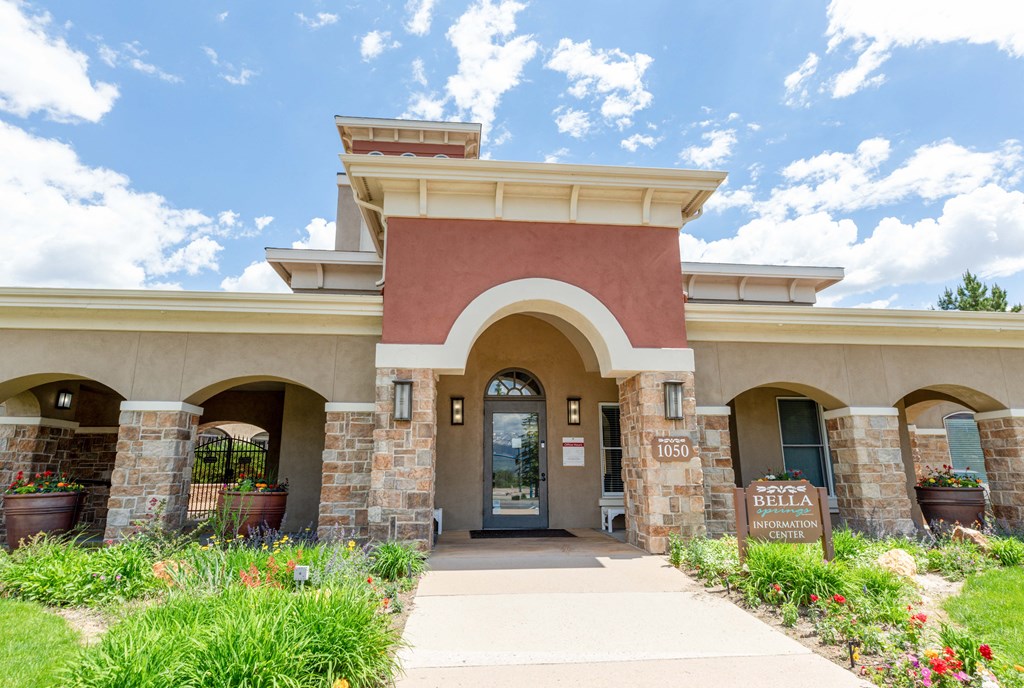 the front entrance of a building with a walkway and flowers