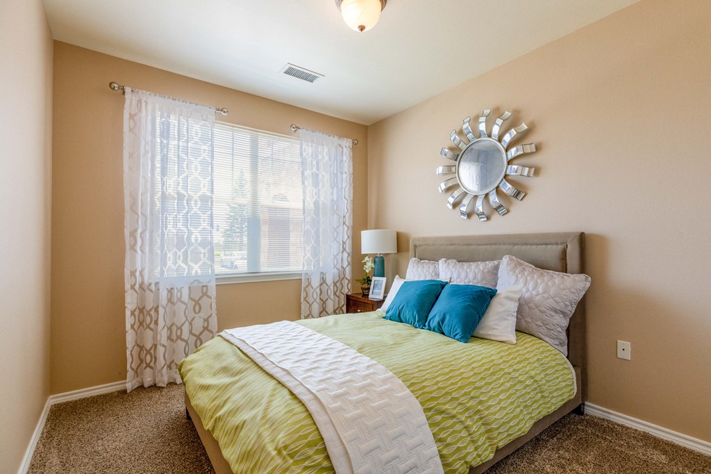 a bedroom with a bed and a sunburst mirror on the wall