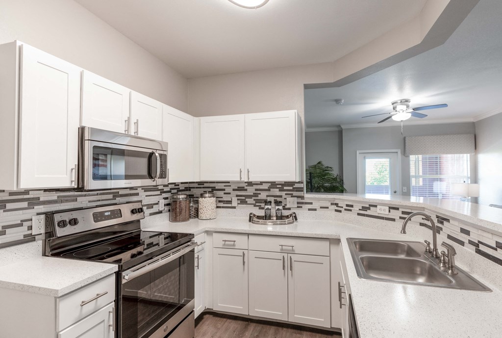 an open kitchen with white cabinets and stainless steel appliances
