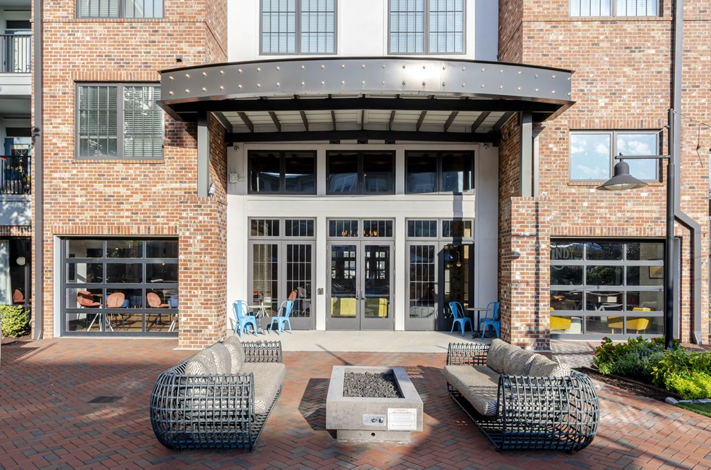 A patio area with a brick wall and a black metal table and chairs