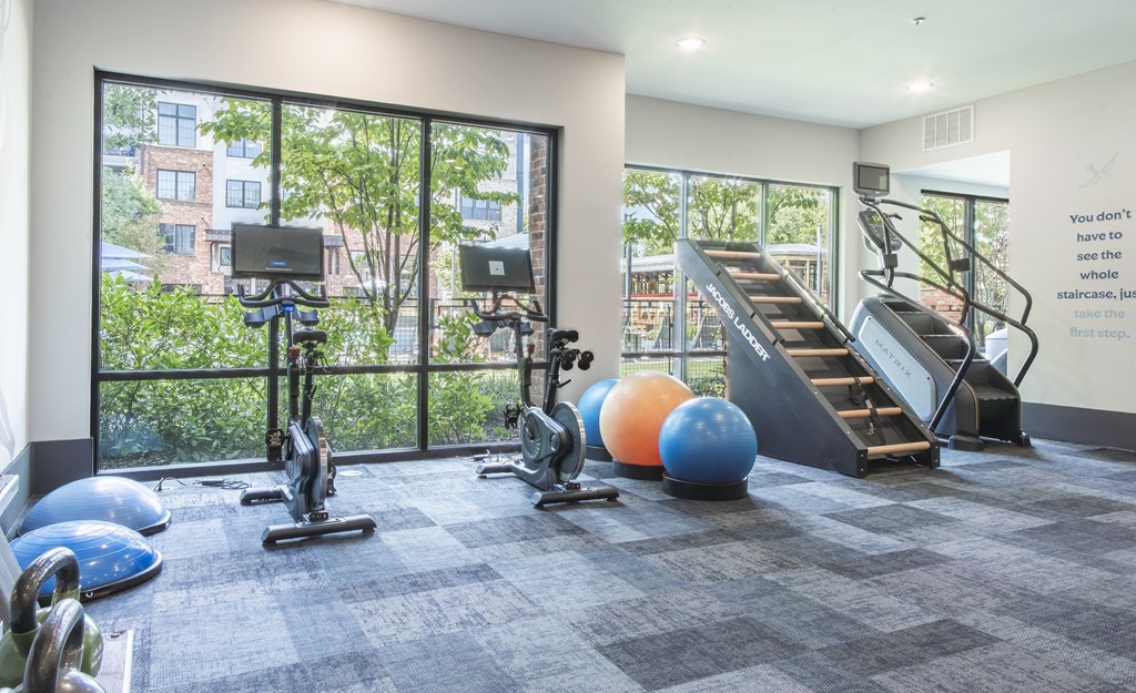 A gym with a variety of equipment including a treadmill, exercise balls, and weights.