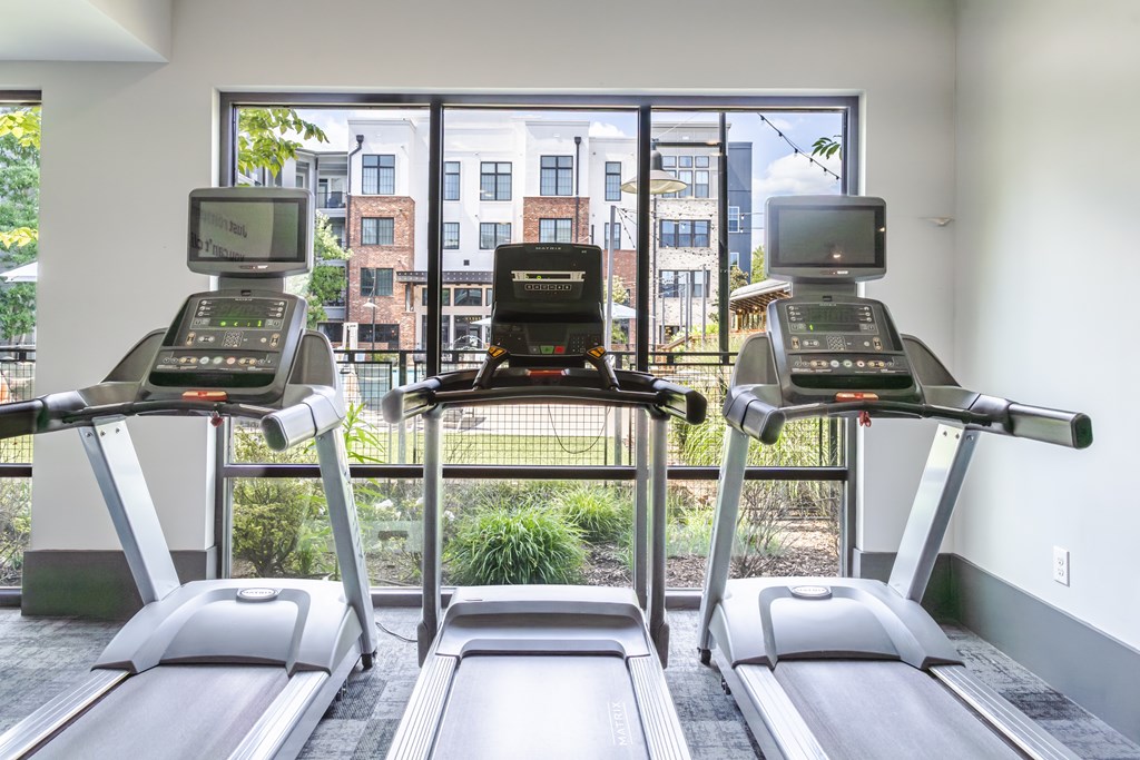 Three treadmills are lined up in a row in a gym