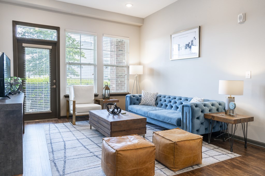 A living room with a blue couch and a wooden floor.