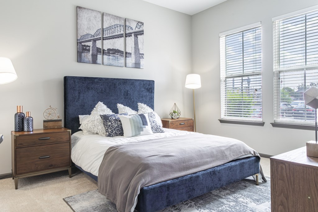 A bedroom with a large bed and a bridge picture on the wall.