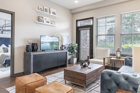 A modern living room with a grey sofa, a wooden coffee table, and a television on a cabinet.