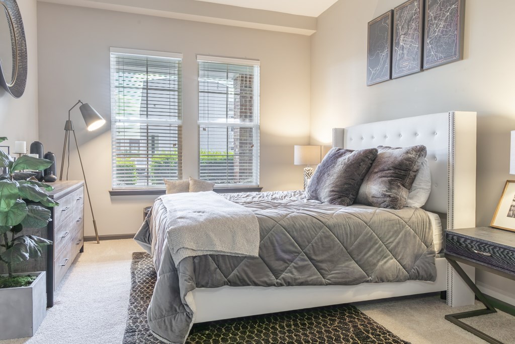 A bedroom with a large bed and a potted plant.