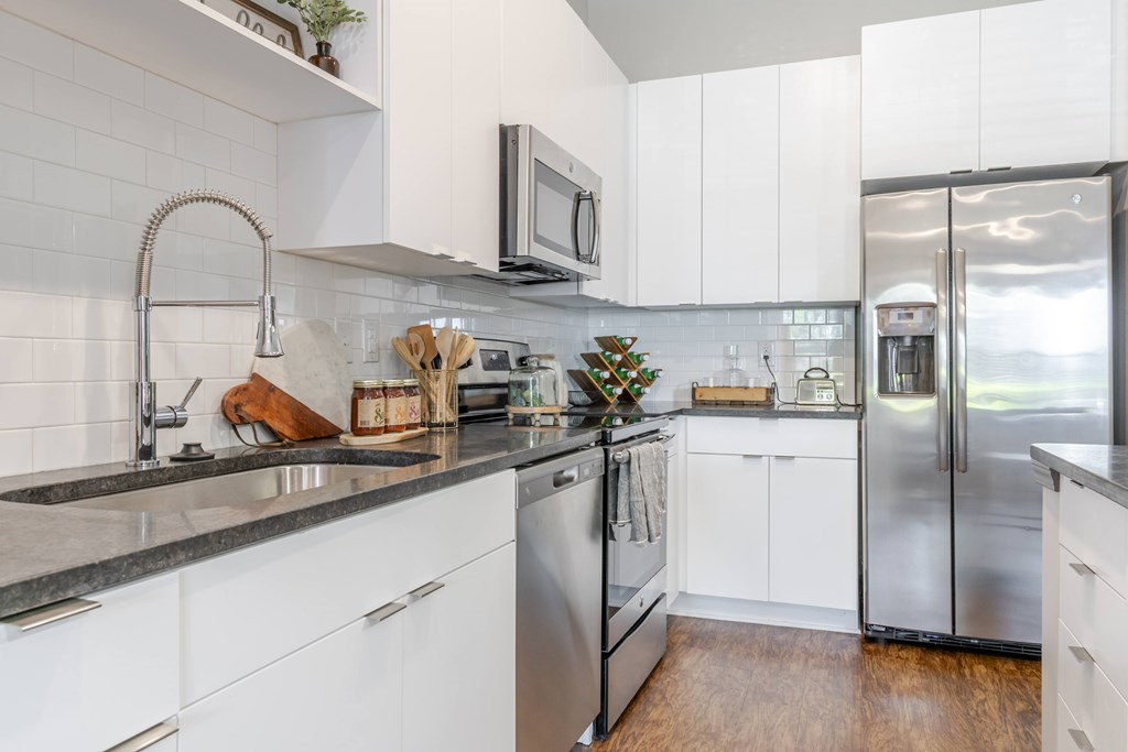 A kitchen with white cabinets and a black fridge.