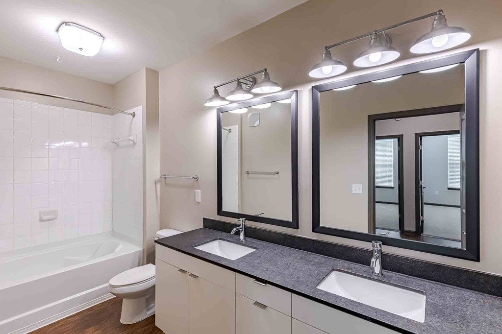 A bathroom with a white tub, sink, and mirror.