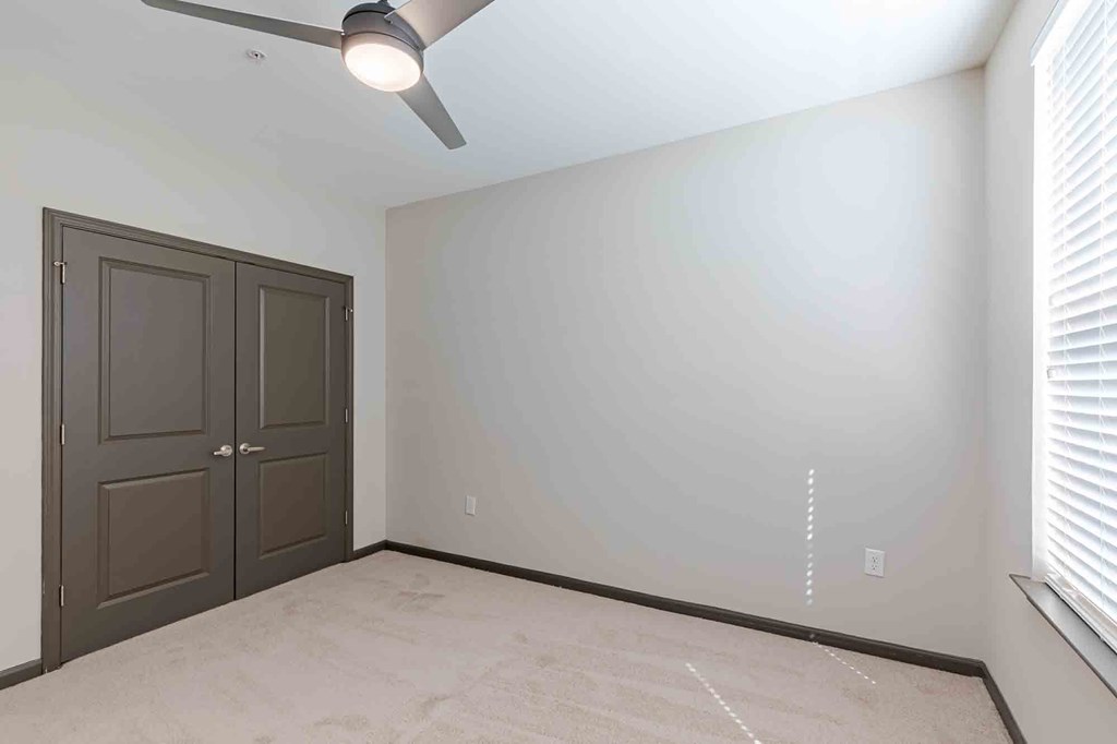 A room with a ceiling fan and a double door.