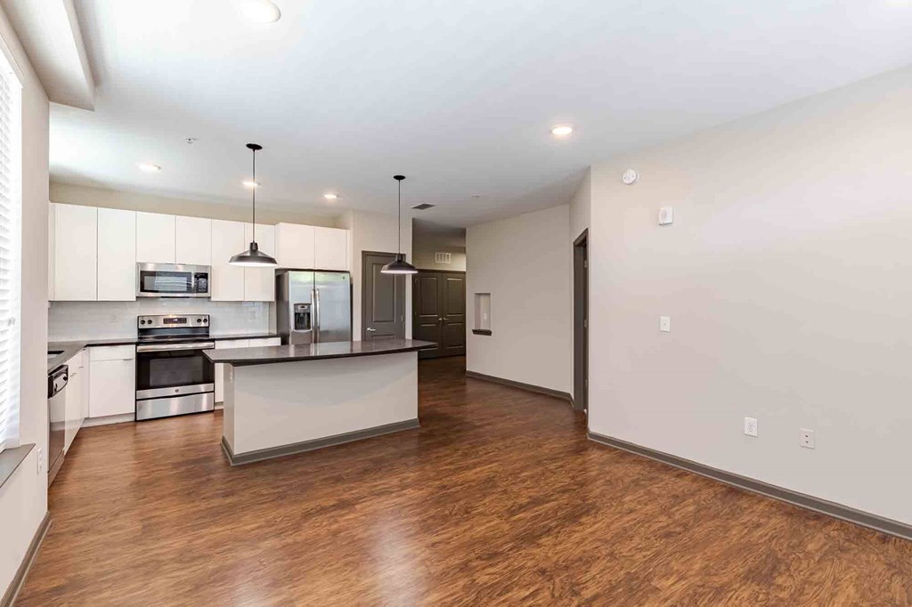A spacious kitchen with wooden floors and modern appliances.