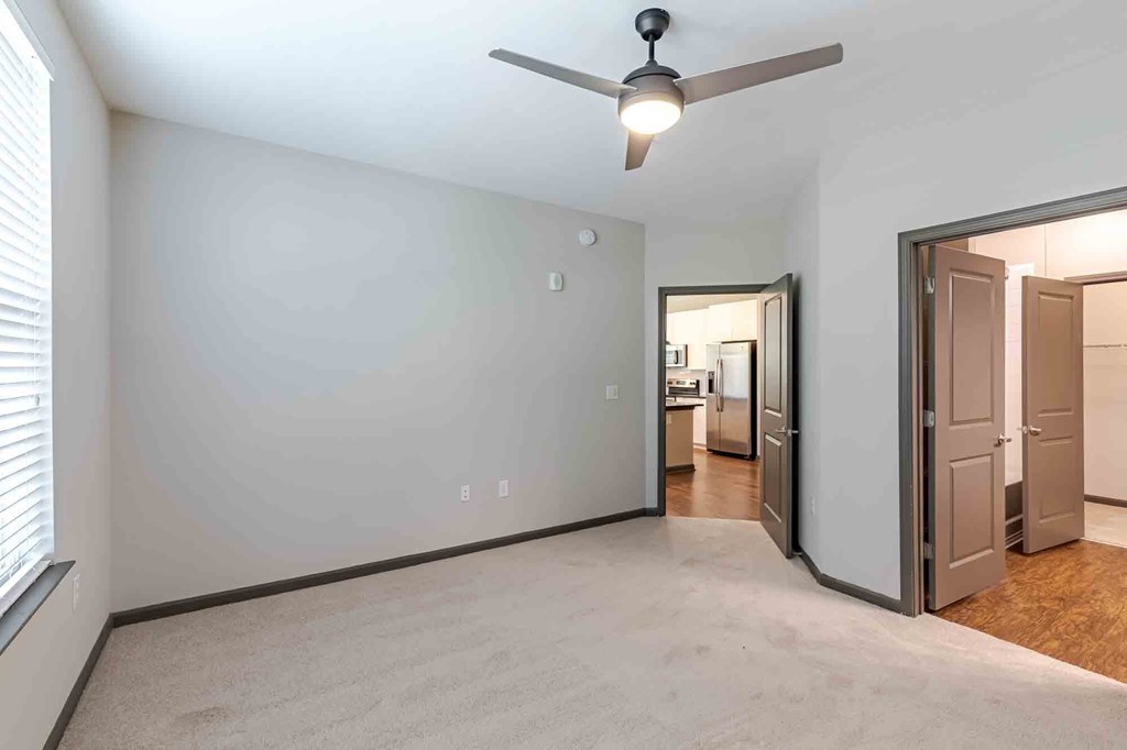 A room with a ceiling fan and a door leading to another room.
