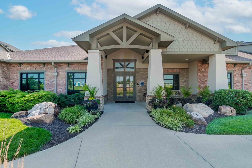 the front of a brick building with a walkway and landscaping