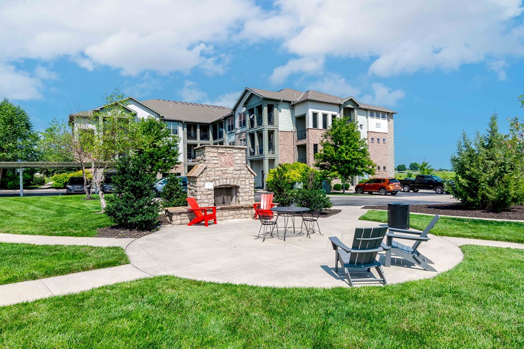 a patio with chairs and a fire pit in front of a building