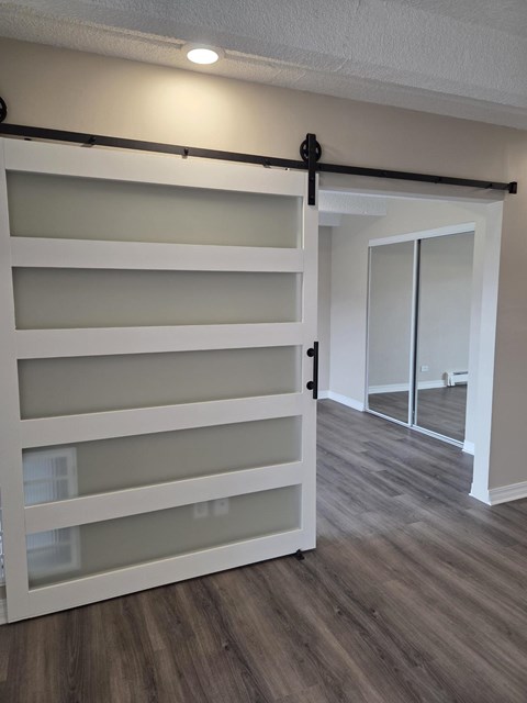 A white sliding barn door in a room with wood flooring.