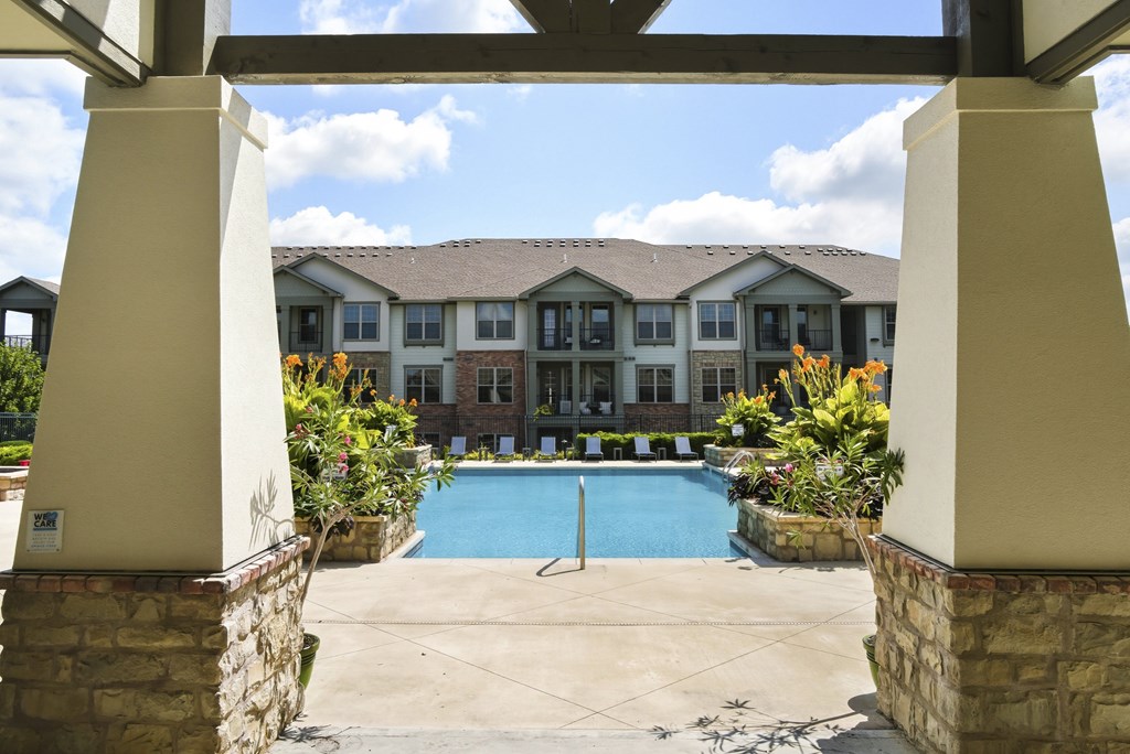 A view of a pool through a covered walkway.