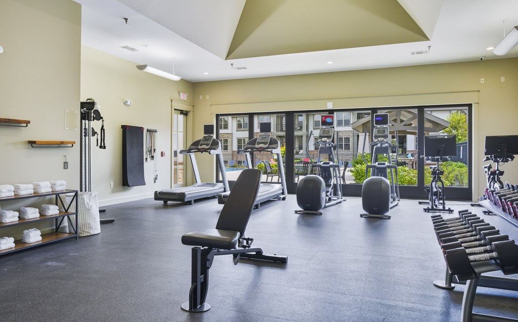 A gym with a variety of equipment including treadmills, weights, and exercise machines.