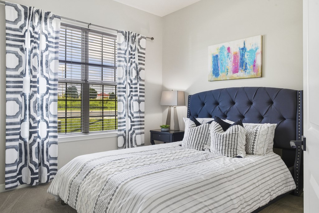 A bedroom with a large bed and a painting on the wall.