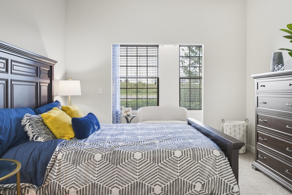 A bedroom with a large bed and a window with blinds.