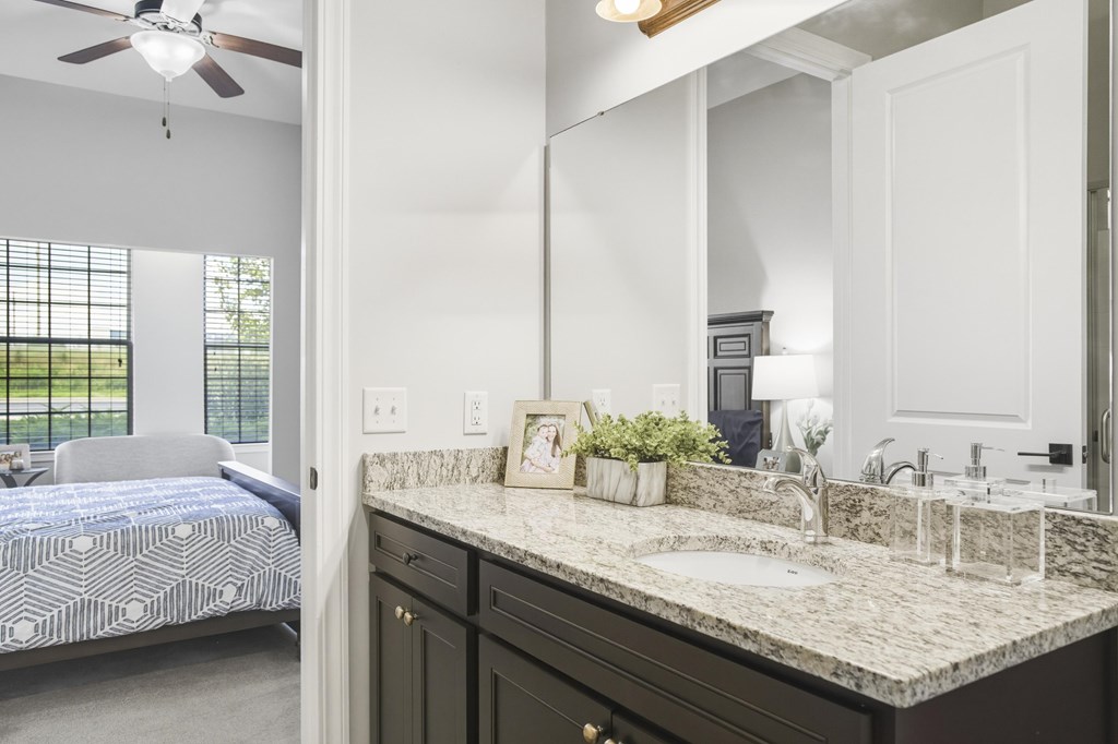 A bedroom with a bed, a vanity, and a window.