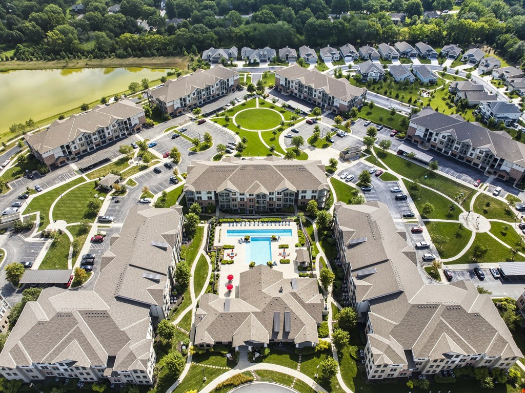 A bird's eye view of a residential complex with a swimming pool in the center.