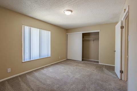 an empty living room with a large window and a closet