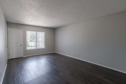 an empty living room with wood floors and a window