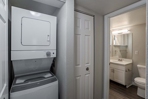 a white washer and dryer in a bathroom with a toilet and a sink