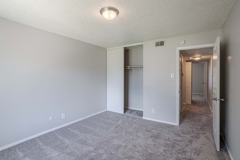 an empty living room with white walls and a hallway to a closet