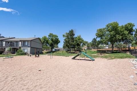 a playground with a swing set and a house in the background