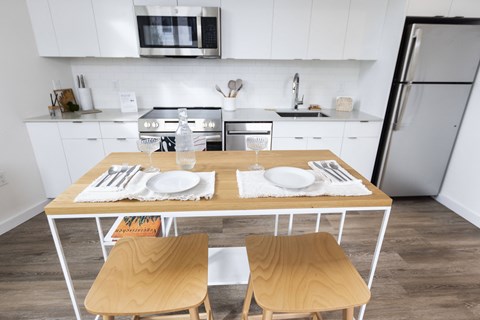 A kitchen with a table set for two with a white plate and silverware.