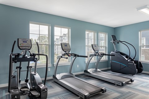 A gym with treadmills, elliptical machines, and a stationary bike.