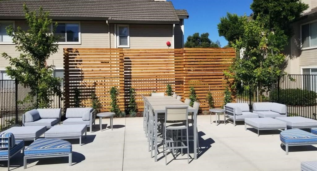 a patio with chairs and tables and a wooden privacy fence