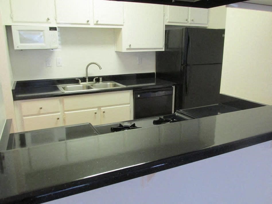 a kitchen with white cabinets and a black counter top
