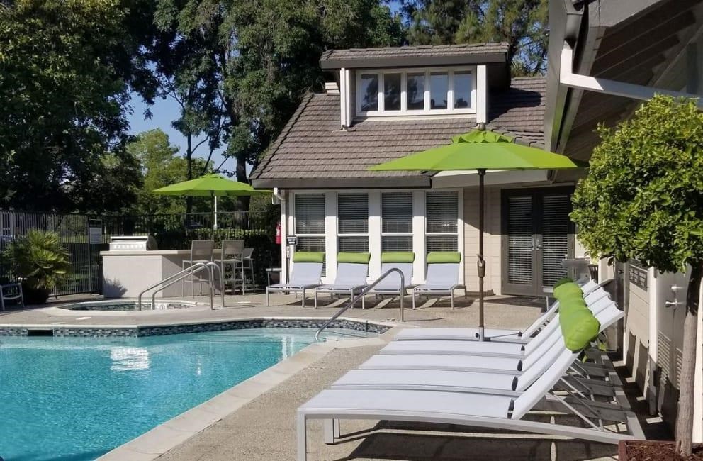 a pool and lounge chairs in front of a house