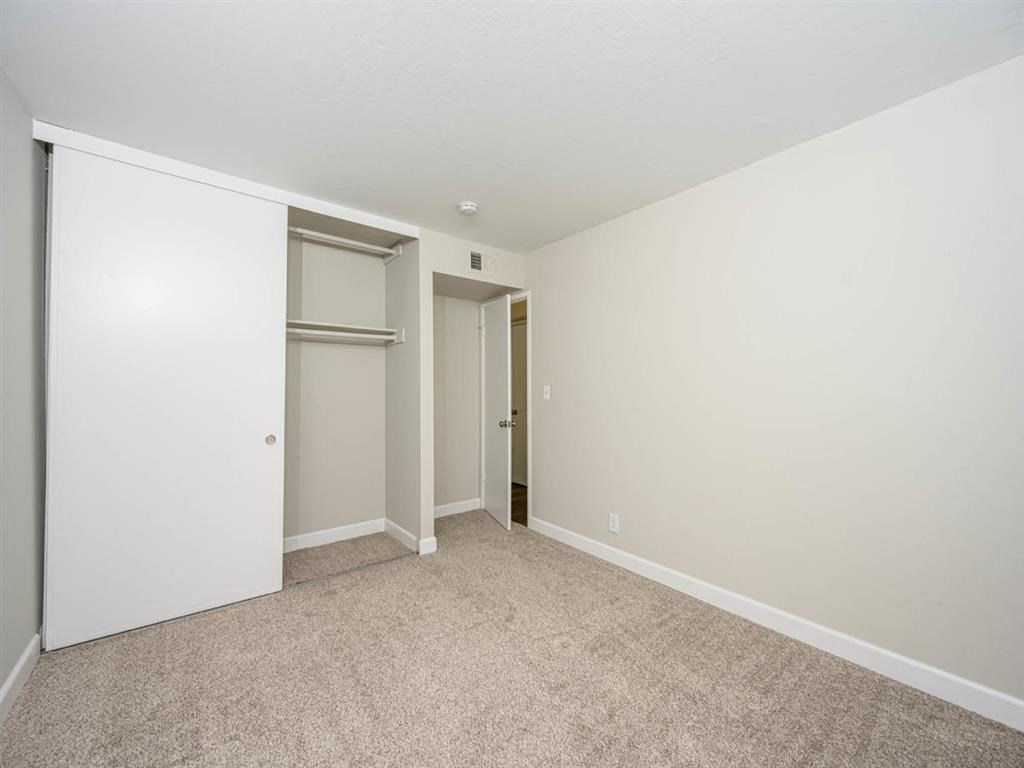 an empty living room with white walls and a door to a closet